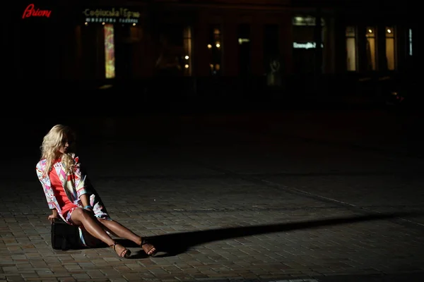 Сексуальная юная брюнетка в черном платье сидит у дороги — стоковое фото