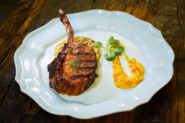 Kuzu kaburga baharat ve beyaz tabakta sos ile kavrulmuş. Sığ dof