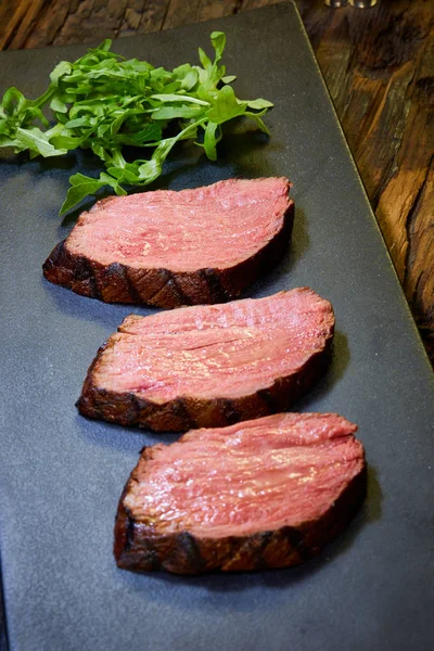 Стейк, разрезанный на куски, приготовленный, чтобы съесть говядину на каменном столе. — стоковое фото