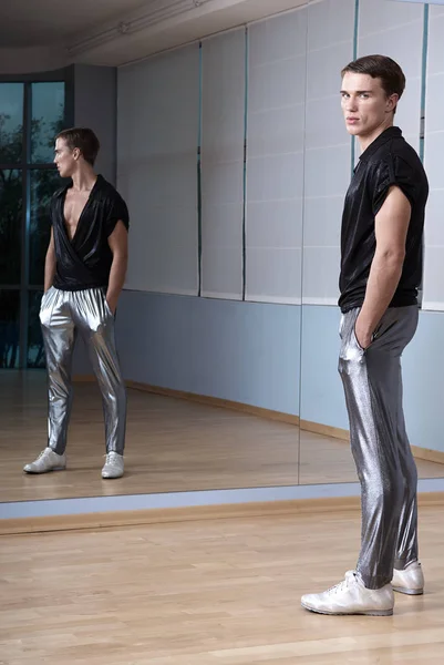 Man in elegant sport suit posing in fitness gym. Young man in silver sport leggings