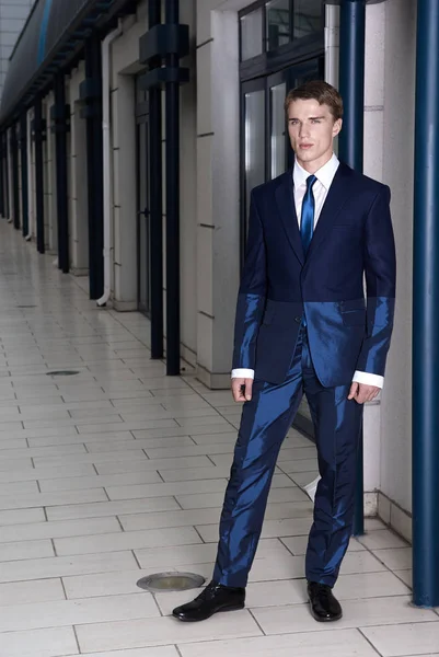 Portrait of an attractive young businessman in urban background wearing blue suit and necktie. Looking to the camera. Classic style. — Stock Photo, Image