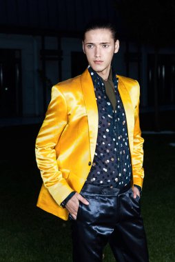 Sarı Ceket daimi yeşil çimenlerin üzerinde çekici şık adam. Kameraya bakıyor. Klasik tarzı. Stüdyo vurdu