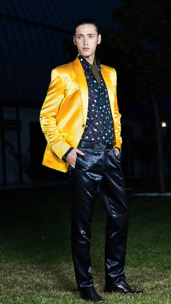 Charmante, elegante man in een gele jas reputatie op groen gras. Op zoek naar de camera. Klassieke stijl. Studio schoot — Stockfoto