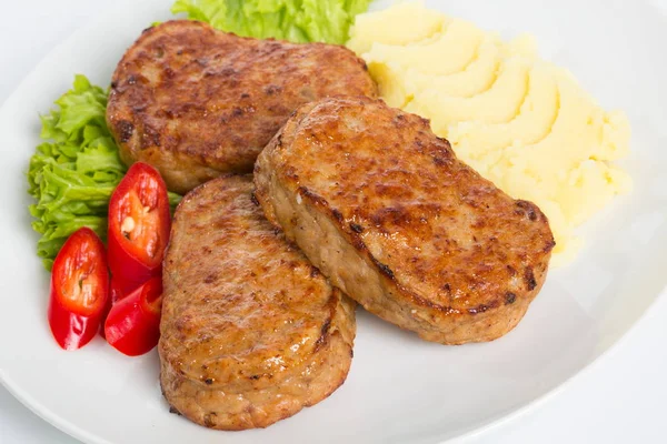 Tres chuletas fritas empanadas con lechuga, puré de papas y pimienta sobre fondo blanco — Foto de Stock