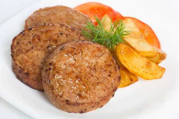 Three fried breaded cutlet with tomatoes and french fries on white background — Stock Photo, Image