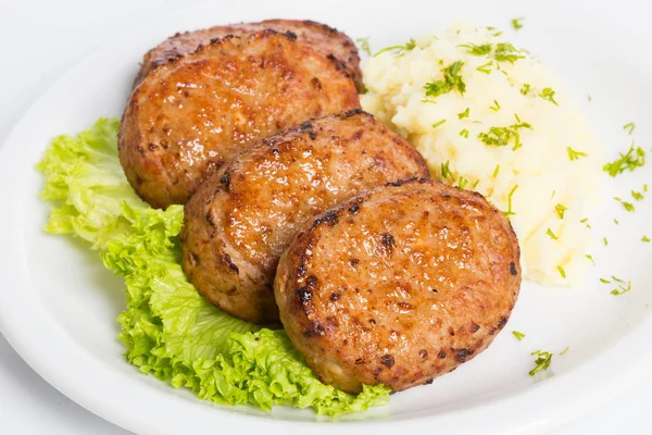 Tres chuletas fritas empanadas con lechuga y puré de papas sobre fondo blanco — Foto de Stock