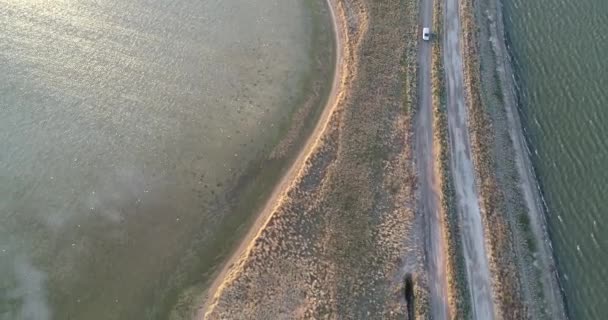 Vista aérea do drone 4K da costa de Azov liman. Offroad carro dirigindo na costa do mar de Azov ao pôr do sol — Vídeo de Stock