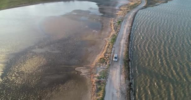 4K aerial drone view of Azov liman coastline. Offroad car driving on Azov sea coast at sunset — Stock Video