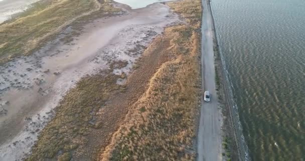 4K aerial drone view of Azov liman coastline. Offroad car driving on Azov sea coast at sunset — Stock Video