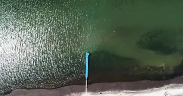 Lazo de vídeo con imágenes aéreas que muestran la vista de pájaro con la gente caminando y broncearse en una playa tropical de Florida bajo sombrillas azules y olas turquesas del océano rompiendo contra la línea costera — Vídeo de stock