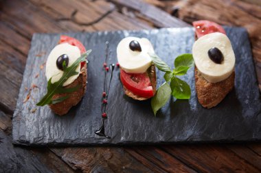 Doğranmış domates, fesleğen, mozzarella peyniri ve balsamik sirke ile İtalyan bruschetta. Taze ev yapımı caprese bruschetta veya crostini siyah taş zemin, kopya alanı üzerinde.