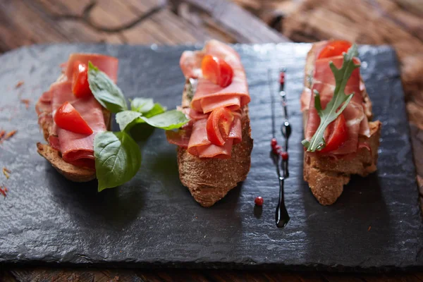 Bruschetta con hamon e salsa su pietra nera — Foto Stock