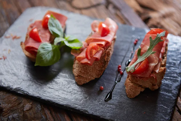 Bruschetta con hamon y salsa sobre piedra negra —  Fotos de Stock