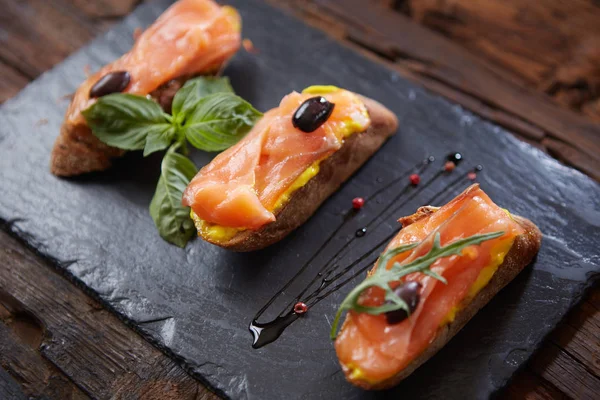 La gustosa bruschetta con salmone su pietra nera — Foto Stock