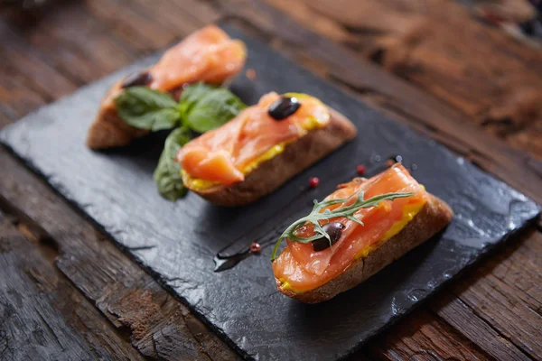 La gustosa bruschetta con salmone su pietra nera — Foto Stock