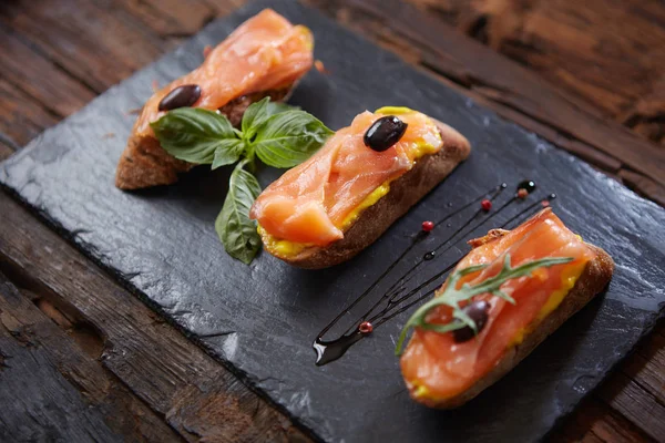 Den välsmakande bruschetta med lax på svart sten — Stockfoto