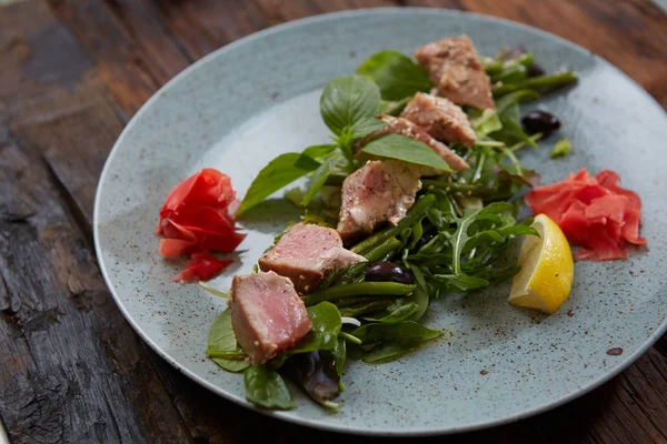 Ottimo cibo: bistecca di tonno al sesamo, lime e insalata fresca primo piano su un piatto in tavola . — Foto Stock