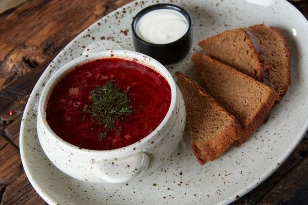 Traditional Ukrainian Russian borscht with white beans on the bowl. Plate of red beet root soup borsch on black rustick table. Beetroot soup Top view. Traditional Ukraine food cuisine — Stock Photo, Image