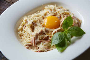 Beyaz tabakta makarna Carbonara parmesan ile.