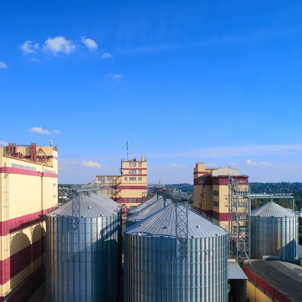 Silo agricolo. Stoccaggio ed essiccazione di cereali, frumento, mais, soia, contro il cielo blu con nuvole . — Foto Stock