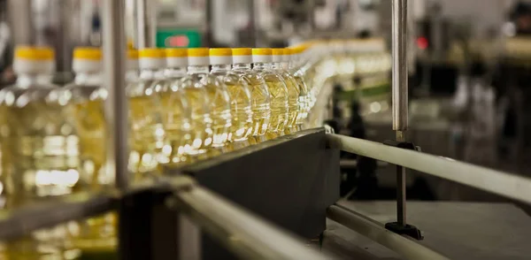 Aceite de girasol en la botella en movimiento en la línea de producción. Dof poco profundo . —  Fotos de Stock