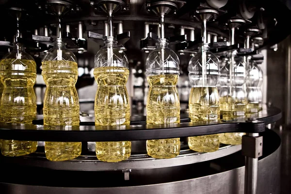 Minyak bunga matahari dalam botol bergerak pada lini produksi. dof dangkal . — Stok Foto