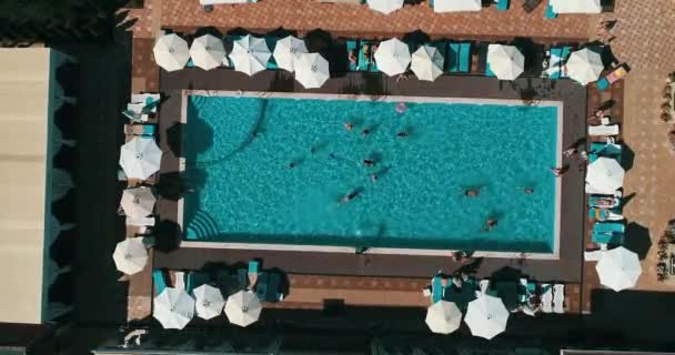 Vista aerea dall'alto della famiglia in piscina dall'alto, madre felice e bambini nuotano su ciambelle ad anello gonfiabili e si divertono in acqua in vacanza in famiglia . — Video Stock