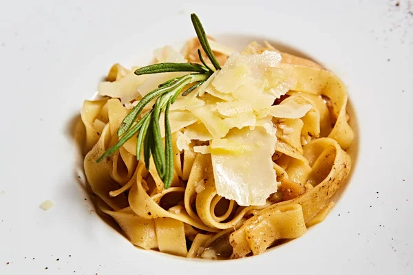 Prato de macarrão italiano close-up com queijo parmesão ralado e folha de manjericão — Fotografia de Stock