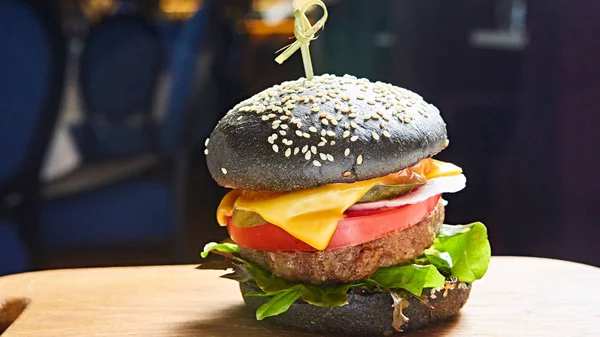 Japansk svart burgare med ost. Ostburgare från Japan med svart bulle på mörk bakgrund. — Stockfoto