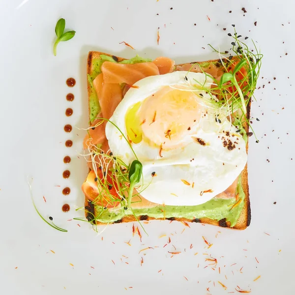 Egg benedict com molho holandês e salmão defumado em torradas. Delicioso café da manhã . — Fotografia de Stock