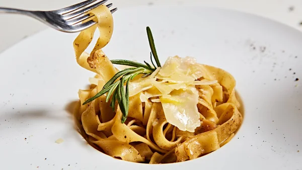 Крупный план итальянской пасты с тертым сыром пармезан и листом базилика — стоковое фото
