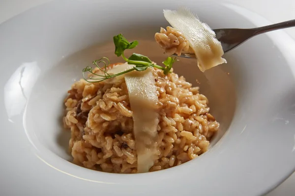 Italian dish risotto with wild white mushrooms and Parmesan cheese in a white plate. — Stock Photo, Image