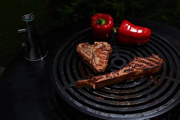 Tomahawk rib beef steak and T-bone on hot black grill. — Stock Photo, Image