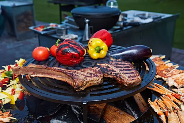 Tomahawk rib beef steak and T-bone on hot black grill. — Stock Photo, Image