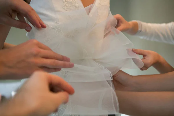 Mãos de namoradas ajudando a noiva a vestir seu vestido — Fotografia de Stock