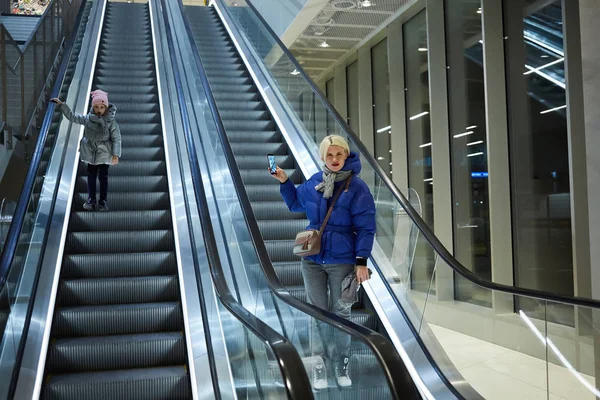 Modern och barnet tillsammans på rulltrappan bakgrund. Terminal, flygplats resor, kärlek vård. — Stockfoto