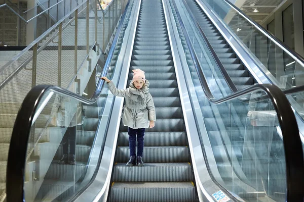 Desde abajo plano de la chica de pie en las escaleras móviles en la terminal . — Foto de Stock
