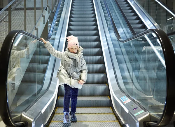 De baixo tiro de menina de pé em movimento escadas no terminal . — Fotografia de Stock