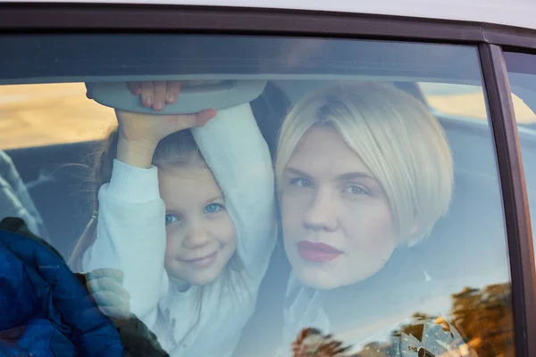 Járműcsalád-koncepció. Anya és lánya egy autó az üvegen keresztül portréja — Stock Fotó