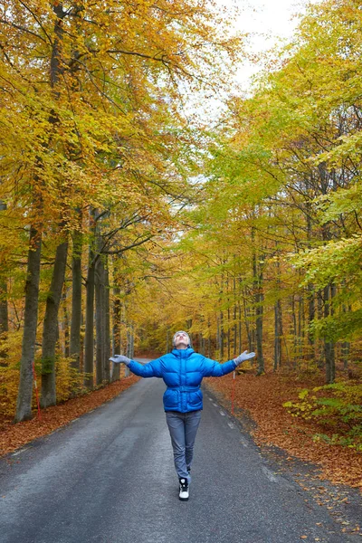 Fiatal nő pózol az őszi erdő, az úton. — Stock Fotó