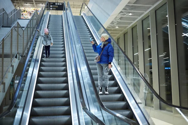 Madre e hijo juntos en el fondo de la escalera mecánica. Terminal, viajes al aeropuerto, cuidado del amor . —  Fotos de Stock