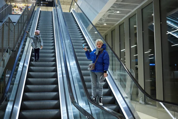 Moeder en kind samen op roltrap achtergrond. Terminal, airport reizen, liefde zorg. — Stockfoto