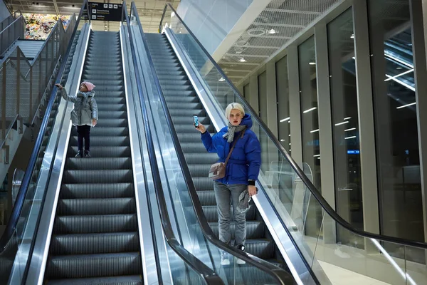 Madre e hijo juntos en el fondo de la escalera mecánica. Terminal, viajes al aeropuerto, cuidado del amor . — Foto de Stock