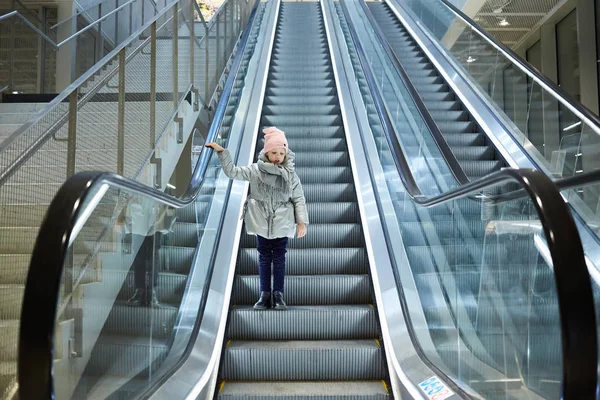 Desde abajo plano de la chica de pie en las escaleras móviles en la terminal . —  Fotos de Stock