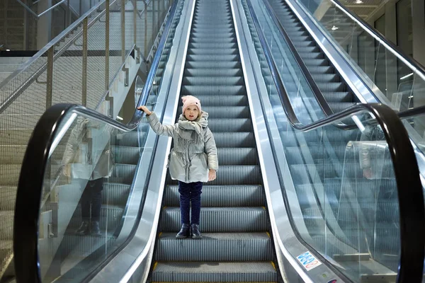 Desde abajo plano de la chica de pie en las escaleras móviles en la terminal . —  Fotos de Stock