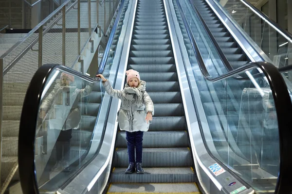 Desde abajo plano de la chica de pie en las escaleras móviles en la terminal . —  Fotos de Stock