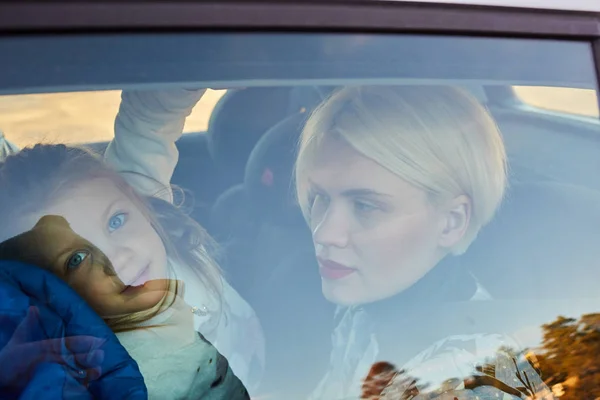 Family concept. Portrait of mother and daughter through the glass of a car