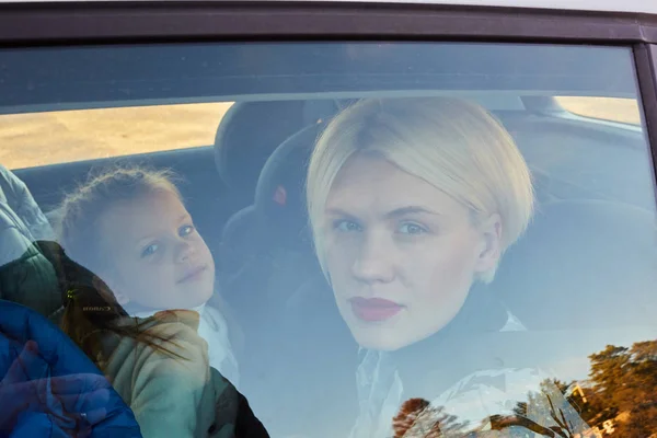 Family concept. Portrait of mother and daughter through the glass of a car