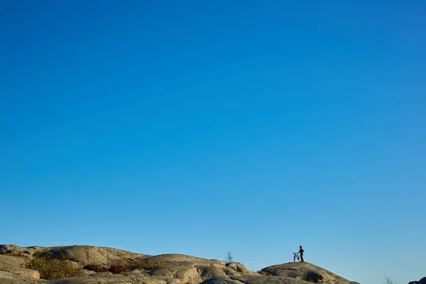 Silueta de joven activo con bicicleta de pie y mirando hacia adelante en las montañas fondo panorámico — Foto de Stock