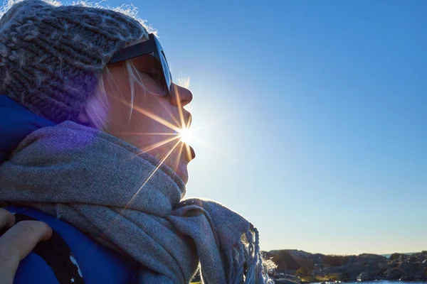 Retrato uma bela jovem mulher em um chapéu de lã eo sol está brilhando da boca — Fotografia de Stock